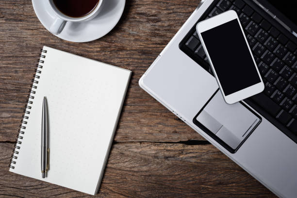 istock wooden table office stuff with notepad, laptop and coffee cup, notepad, pen, smartphone top view shot 955062232