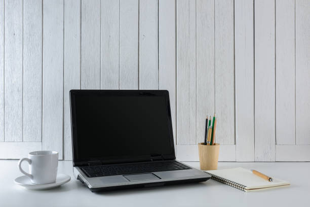 istock workplace background with Blank white screen modern laptop computer. White wooden vintage blackground 955069308