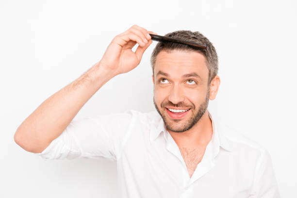 istock Handsome young man combing his hair with comb 955070366