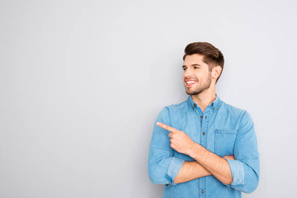 istock Cheerful young man pointing away on gray background 955078508