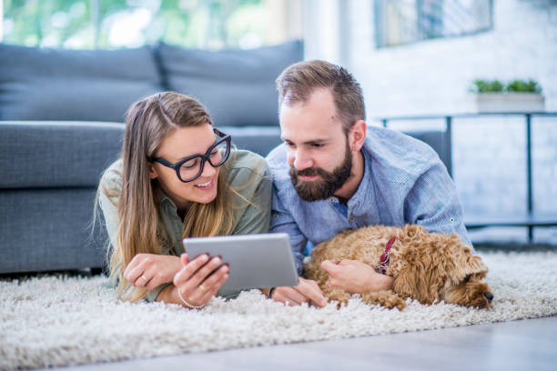 istock Couple lying on the carpet looking at tablet 955078748