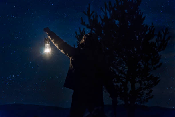 homme de woodman tenant lampe à gaz en forêt sous les étoiles dans la nuit en forêt - lanterne photos et images de collection