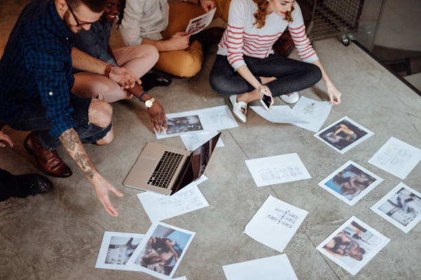 istock Creative people looking at project plans laying on floor 955084728