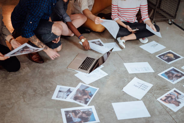 istock Creative people looking at project plans laying on floor 955085020