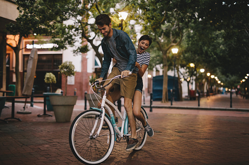 Young couple having fun in the city on bicycle. Happy young couple on bike ride.