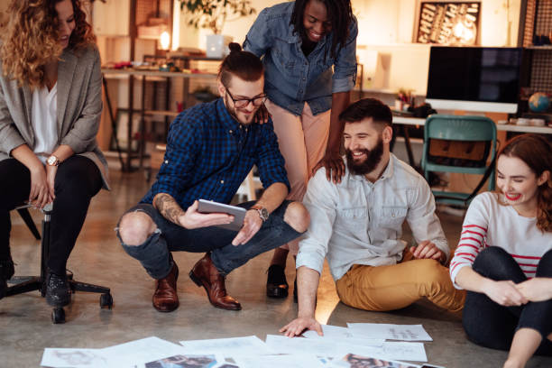 istock Creative people looking at project plans laying on floor 955085248