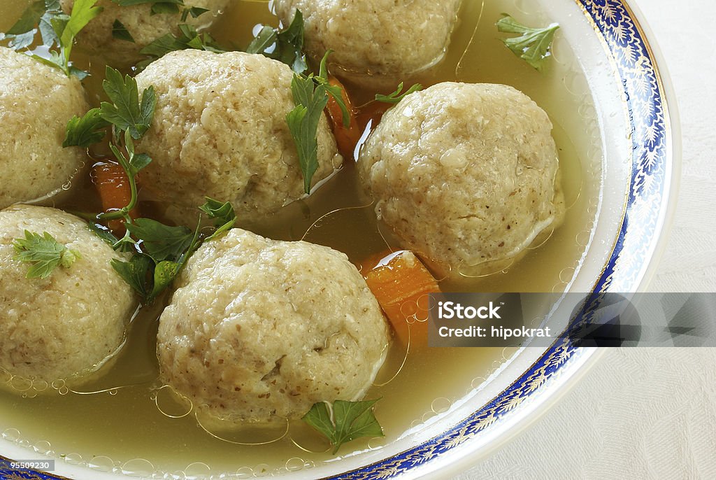 Close-up of Matzo ball soup decorated with herbs and carrots Matzah balls  are a traditional Ashkenazi (East-European Jewish) dumpling made from matzah meal.  Usually are served with chicken broth as matzah ball soup. Matzo Ball Stock Photo