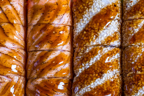 background of sushi cooked from fresh fish, half of which is visible texture, and the other is sprinkled with sesame and filled with syrup