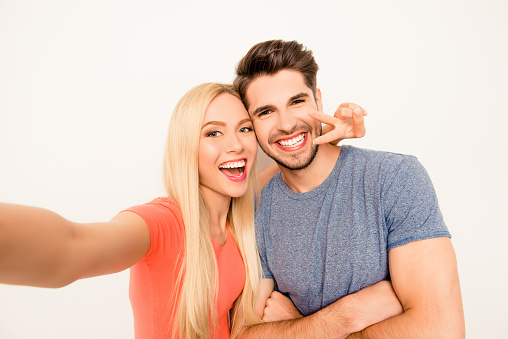 Happy man and woman having fun and showing two fingers while shooting