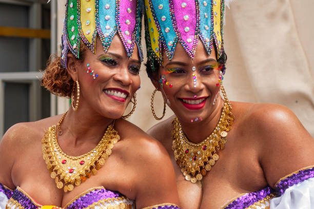 Carnival celebration event at Curacao, colourful dressed woman smiling during parade Willemstad, Curacao - February 11, 2018: portrait of two joyful women dressing colourful costumes during the traditional carnival parade (Grand carnival parade) at the caribbean island of Curacao. Thousands of people march each year at the parade, dancing through the streets of Willemstad, wearing colourful clothes and having lot of fun. curaçao stock pictures, royalty-free photos & images