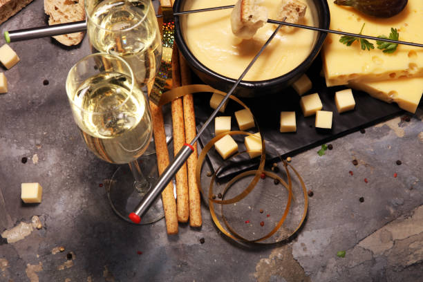 istock Gourmet Swiss fondue dinner on a winter evening with assorted cheeses on a board alongside a heated pot of cheese fondue 955123760