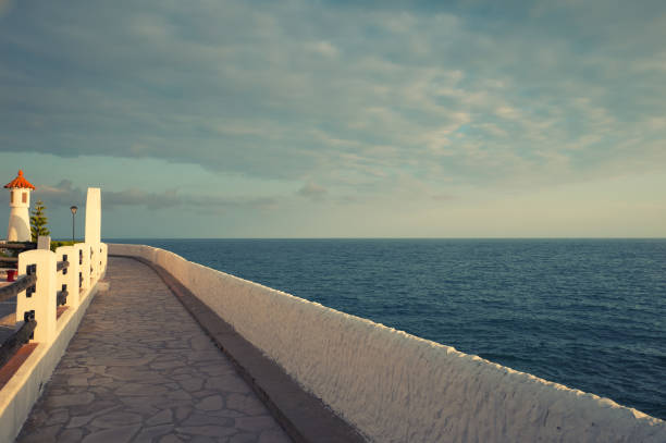 Sidewalk by the sea with a light house in Vilanova i la Geltru near Barcelona, Spain. Jogging path along the coast line.