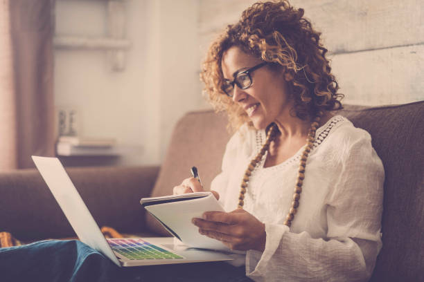 istock nice woman type on a laptop working at home free and happy. taking notes on paper 955132030