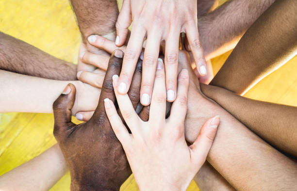 top view of multiracial stacking hands - international friendship concept with multiethnic people representing peace and unity against racism - multi racial love and integration between diversity - community teamwork human hand organization imagens e fotografias de stock