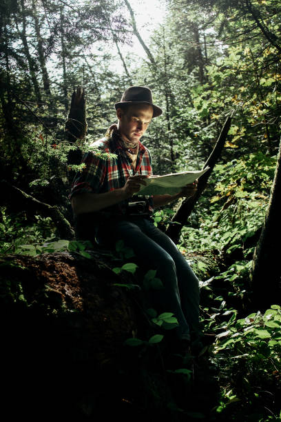 istock stylish hipster traveler exploring map with compass in sunny forest in the mountains 955133348