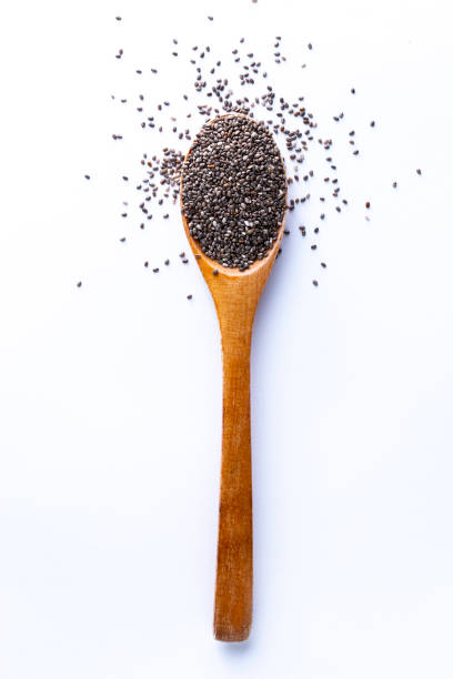 Spoon full of chia grains on white background Flat lay of wooden spoon filled with small seeds of chia lying on white backgroun chia seed photos stock pictures, royalty-free photos & images