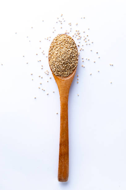 spoon full of quinoa grains on white background - quinoa spoon wood photography imagens e fotografias de stock