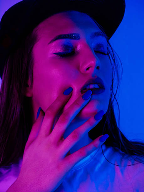 istock Beautiful Woman with Sparkles on her Face in ultraviolet light 955139950