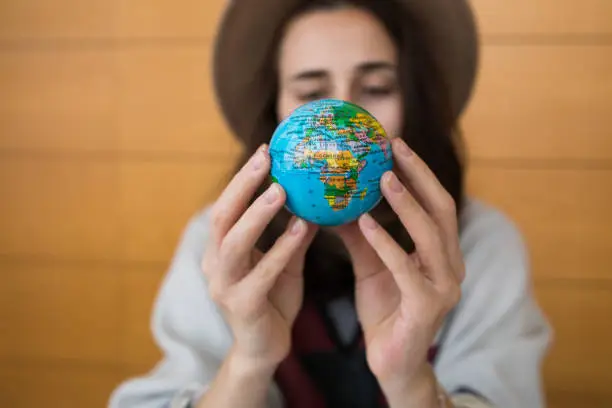 Young girl looking at a small model of planet earth that she is holding in her hands.  Trying to decide what destination should she visit next.