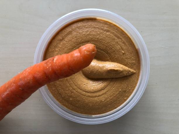 Carrot Resting on Tub of Fresh Hummus
