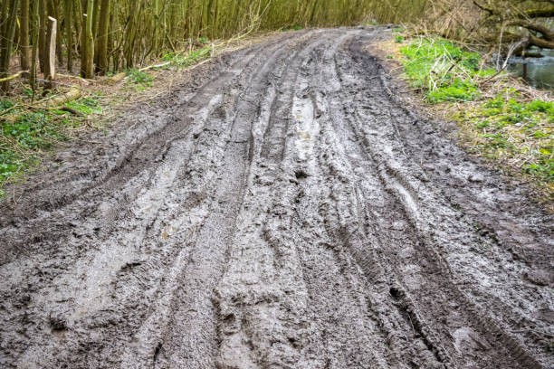 Extremely muddy trail with messy tire tracks next to River Cole in Whelford, England