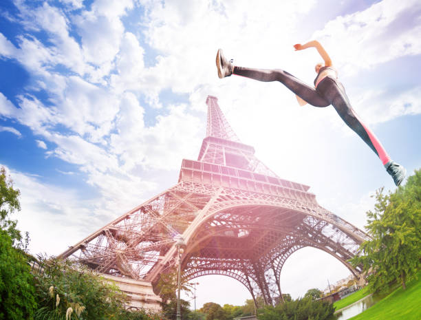 Dynamic shot from low angle of young talented sportswoman jumping near Eiffel Tower