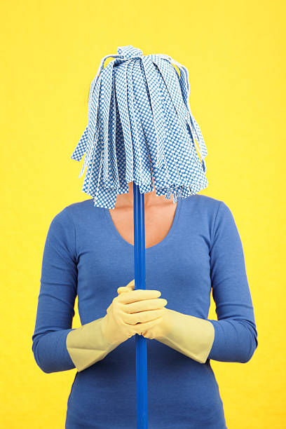 Closeup photo of asian woman housekeeper standing while holding mop