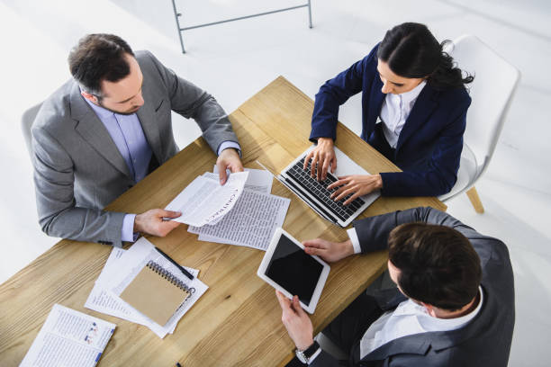 istock high angle view of businesspeople working with gadgets in office 955157910