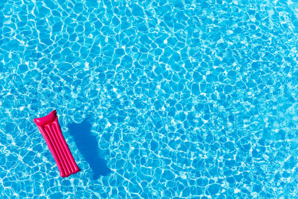 materasso gonfiabile rosa galleggiante sulla superficie dell'acqua - swimming pool foto e immagini stock