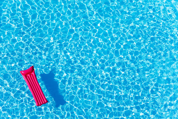 pink inflatable mattress floating on water surface - em cima de imagens e fotografias de stock