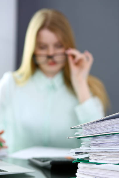 istock Bookkeeper or financial inspector  making report, calculating or checking balance. Binders with papers closeup. Audit and tax service concept. Green colored image backgroun 955165750