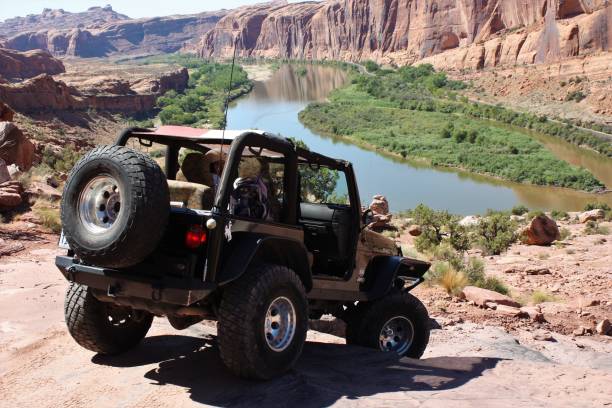 jeep rubicon en el camino del borde moab con vistas al río colorado. - slickrock trail fotografías e imágenes de stock