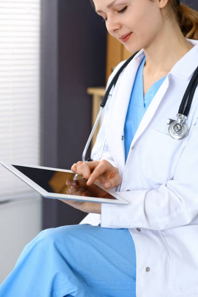 istock Woman doctor using white tablet computer while working in hospital 955166950