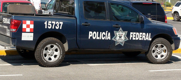 Scene Of People Standing Talking To One Another, Looking Around And Mexican Federal Police Land Vehicle Parked At Acapulco International Airport In Guerrero Mexico