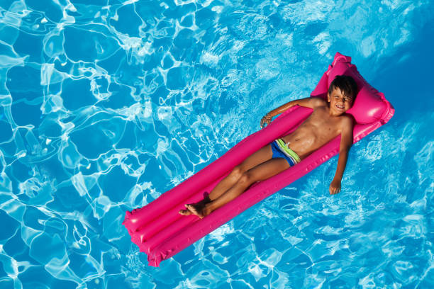istock Boy sunbathing on inflatable lounge in the pool 955169832