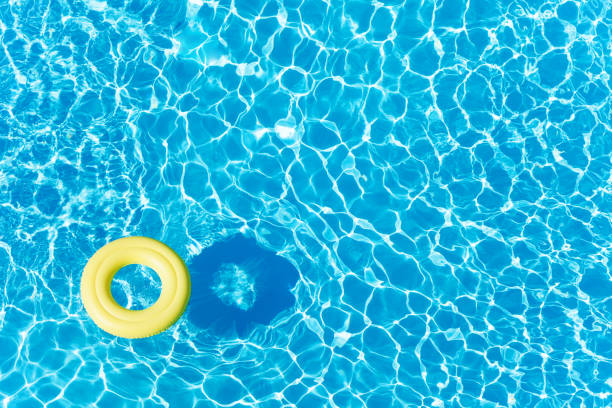 Empty rubber ring floating on blue water surface Top view picture of empty yellow rubber ring floating on blue water surface with copy-space water rings stock pictures, royalty-free photos & images