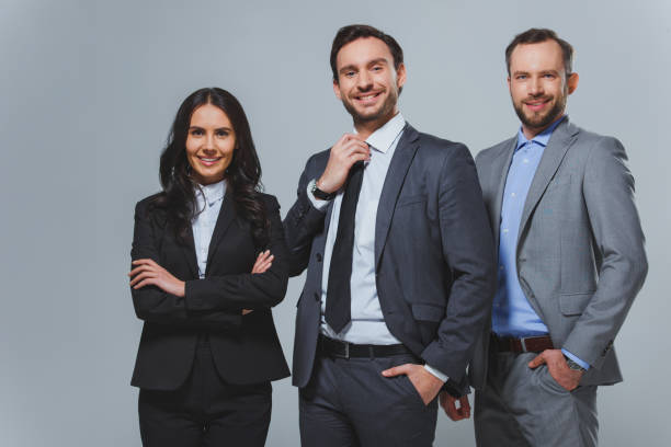 istock smiling business colleagues looking at camera isolated on grey 955172826
