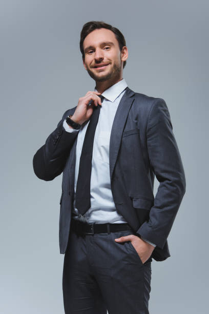 istock smiling handsome businessman fixing tie isolated on grey 955175236