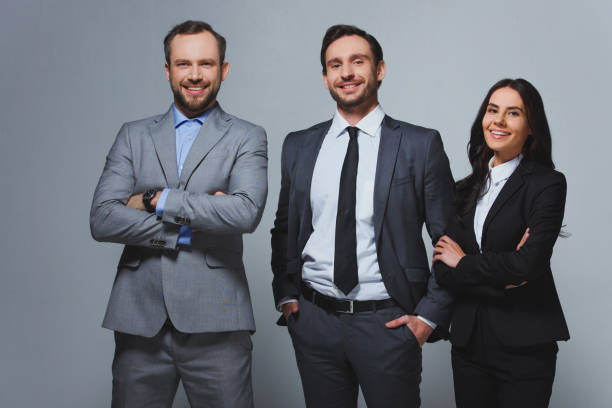 istock smiling businesspeople looking at camera isolated on grey 955175690