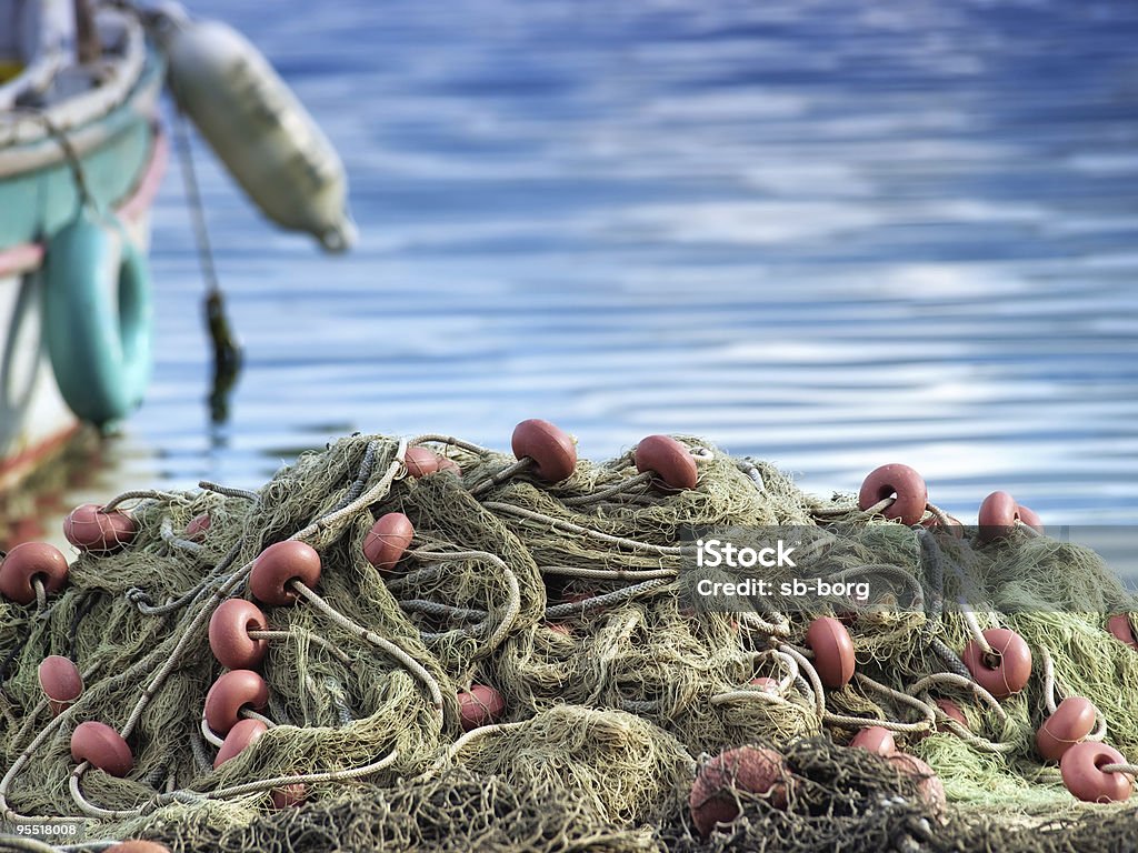 A mass of fishing nets by a boat Heap of fishing net next to the coast somewhere in Croatia. Adriatic Sea Stock Photo