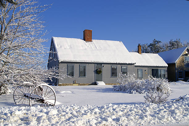 House covered in snow with two chimneys and many windows stock photo