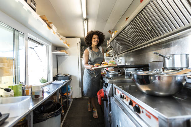 African woman cooking inside of food truck African woman cooking inside of food van, preparing sandwiches. market vendor photos stock pictures, royalty-free photos & images