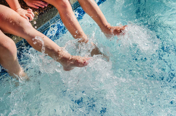 Children's feet splashing in pool water stock photo