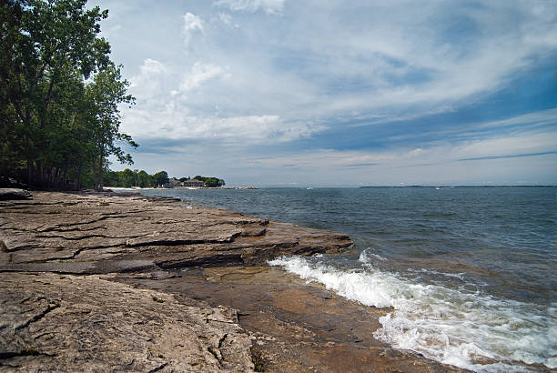 Lakeside view of waves, a rocky shoreline and cloudy sky stock photo