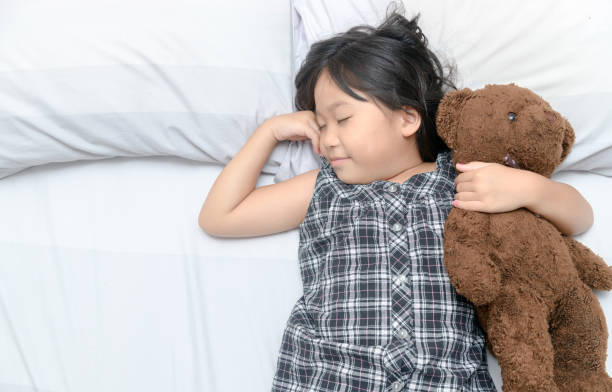 istock Cute girl sleeping on bed with teddy bear 955237926