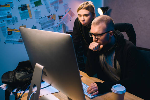 istock serious couple of hackers working with computer together in dark room 955253106