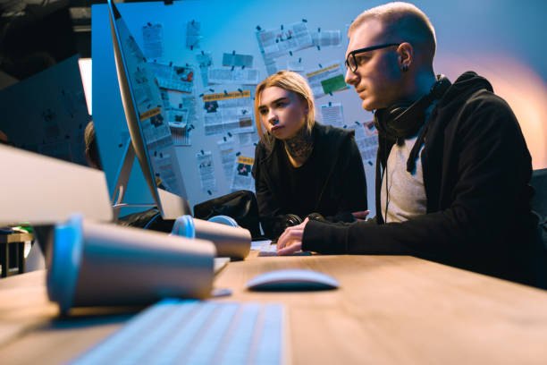 istock thoughtful couple of hackers working with computer together in dark room 955255360