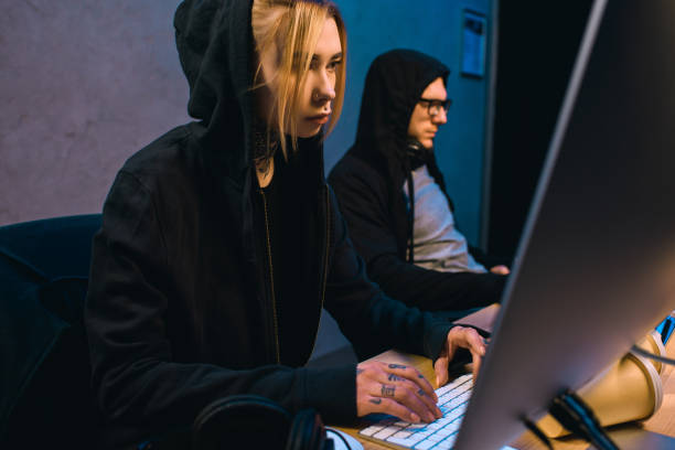 istock serious female hacker working on new malware with accomplice  in dark room 955255684