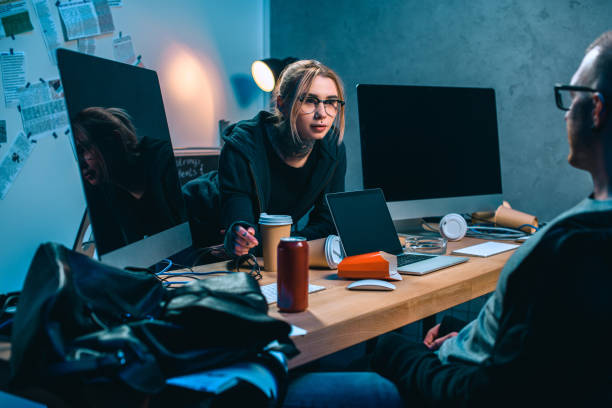 istock couple of hackers talking at workplace in dark room 955259620
