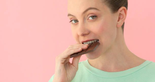 istock Woman eating chocolate over pink background 955259804